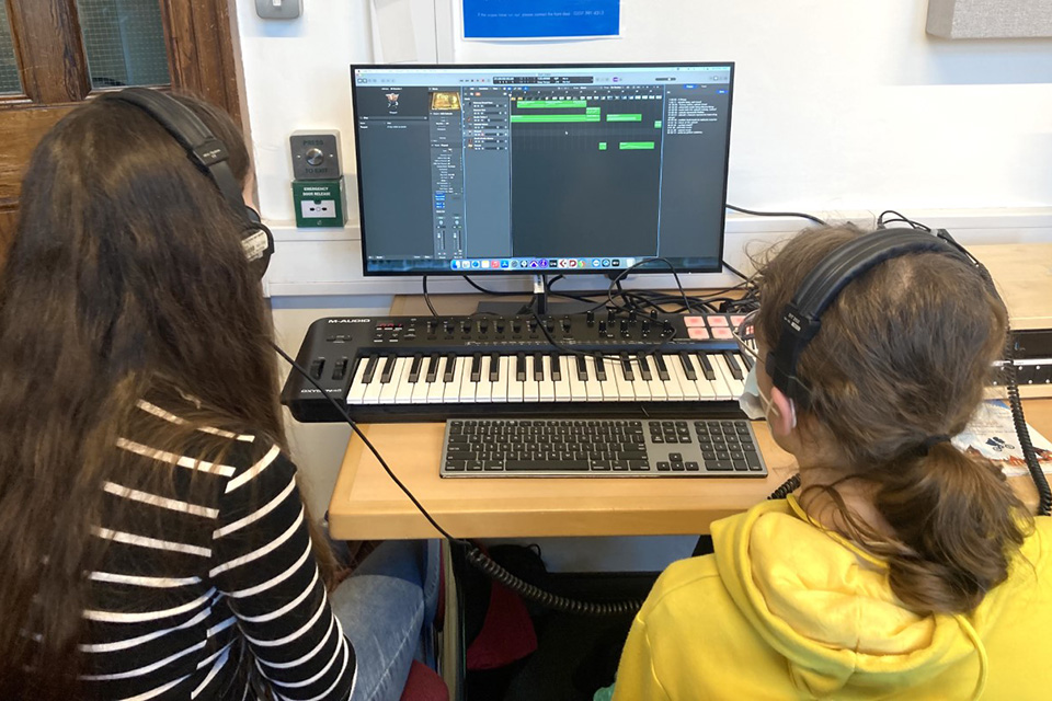 Two young participants use a computer and keyboard during a composition for screen session.test